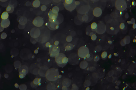 Defocused bokeh lights of different sizes and colors on a dark background.の写真素材