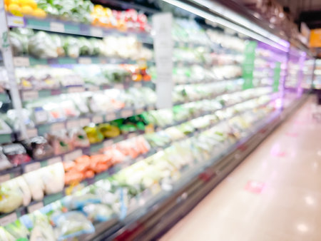 Blurred view of a grocery store aisle showcasing various fresh vegetables in refrigeration shelvesの写真素材