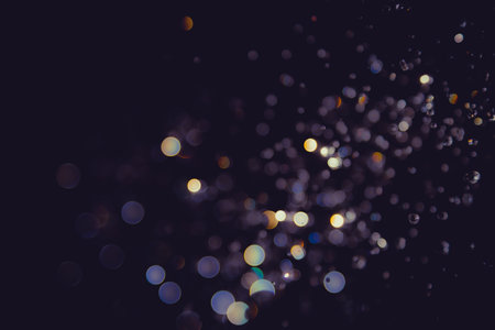 Abstract bokeh lights with colorful circles on dark background, creating a dreamy and festive atmosphere.の写真素材