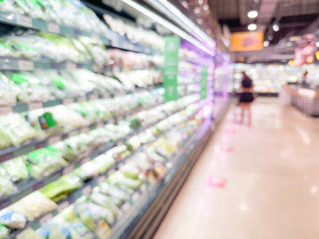 Blurred view of a grocery store aisle showcasing various fresh vegetables in refrigeration shelvesの写真素材
