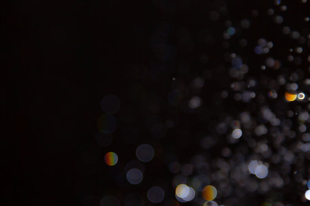 Abstract bokeh lights with colorful circles on dark background, creating a dreamy and festive atmosphere.の写真素材