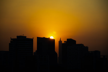 stunning silhouette of a city skyline against a vibrant orange sunset. The tall buildings are outlined against the bright sky, creating a dramatic and captivating scene backgroundの写真素材