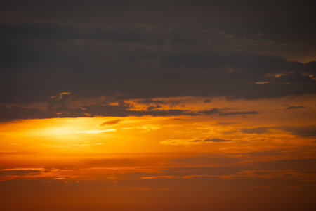 The sun dips below the horizon, casting a golden glow over the calm sea. A gentle breeze ruffles the water as a lone sailboat glides peacefully across the bay. Seagulls cry overhead, adding to the tranquil atmosphere.の写真素材