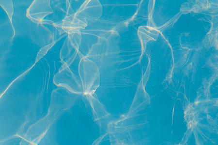 Close-up of vibrant blue swimming pool water with bright sunlight reflections creating dynamic patterns.の写真素材