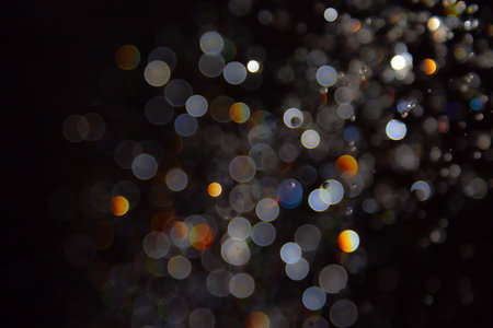 Abstract bokeh lights with colorful circles on dark background, creating a dreamy and festive atmosphere.の写真素材