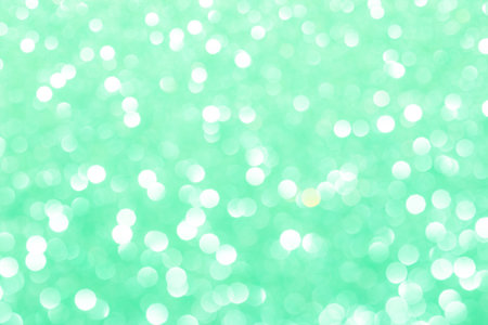 Close-up of sparkling green glitter texture with shimmering lights and reflective surfaces.の写真素材