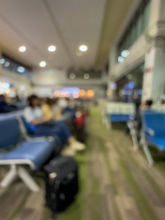 blurred image of an airport lounge, capturing the calm before the flight. Passengers are seen relaxing on comfortable chairs while waiting for their boarding call.の写真素材