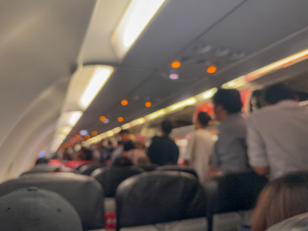 Blurred Airplane Cabin Interior showing overhead lights, seating, and passengers in a subtle, out-of-focus perspective.の写真素材
