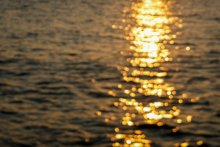 blurred bokeh effect abstract image capturing the golden reflections of sunlight on water, creating a dreamyの写真素材