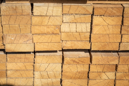 Stacked wooden planks in a lumberyard, various shades and textures, neatly arranged.の写真素材