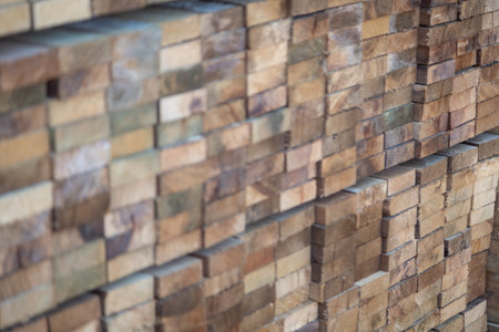 Stacked wooden planks in a lumberyard, various shades and textures, neatly arranged.の写真素材