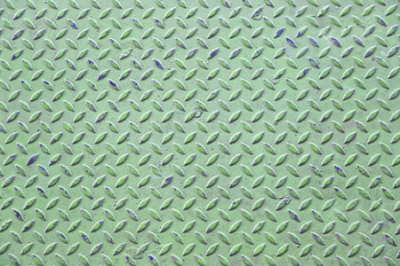 Green diamond plate metal surface with visible wear and scratchesの写真素材