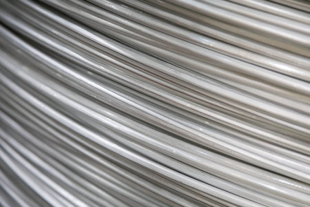 Close-up of coiled aluminum wires with a smooth surface and layered overlapping pattern, soft lighting.の写真素材
