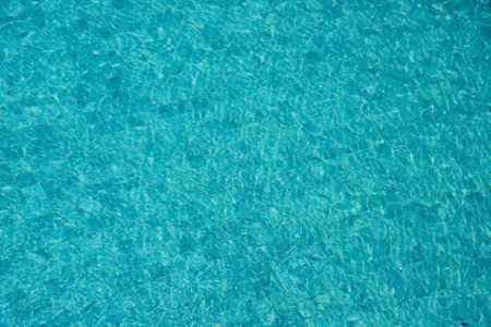 Vibrant blue water surface with shimmering reflections and ripples under sunlight.の写真素材