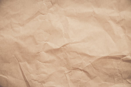 close-up of crumpled brown paper, revealing a texture reminiscent of aged parchment. The deep creases and uneven surface create a sense of time and history.の写真素材