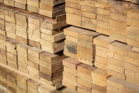 Stacked wooden planks in a lumberyard, various shades and textures, neatly arranged.の写真素材