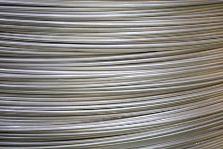 Close-up of coiled aluminum wires with a smooth surface and layered overlapping pattern, soft lighting.の写真素材