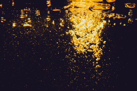 Abstract blurred golden bokeh lights against a dark background creating a warm atmosphere.の写真素材
