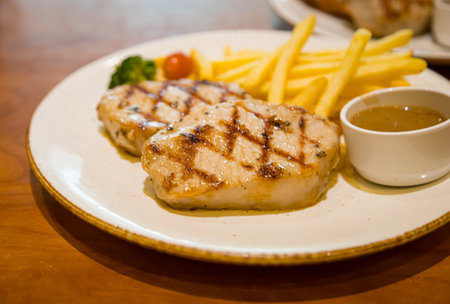 Grilled Pork Steak Served with French Fries and Vegetablesの写真素材