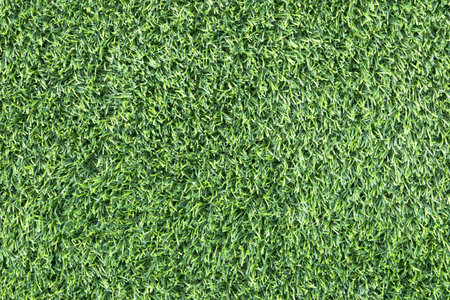 close-up of a lush, green artificial turf. The synthetic blades of grass are perfectly aligned and create a uniform, carpet-like texture backgroundの写真素材