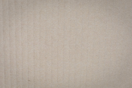 Textured beige corrugated cardboard surface with vertical ridges and subtle shading.の写真素材