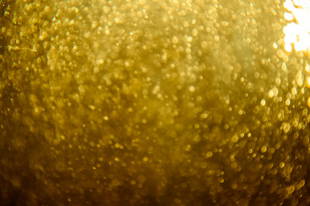 Abstract blurred golden glitter texture with sparkling bokeh lights creating a festive background.の写真素材