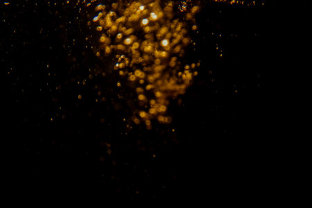 Abstract blurred golden bokeh lights against a dark background creating a dramatic and festive atmosphere.の写真素材