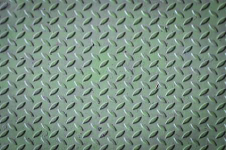 Green diamond plate metal surface with visible wear and scratchesの写真素材