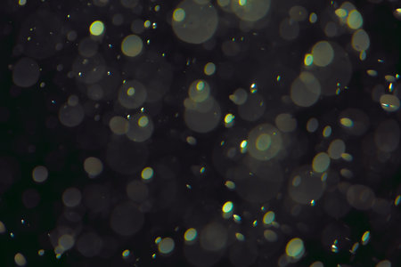 Defocused bokeh lights of different sizes and colors on a dark background.の写真素材