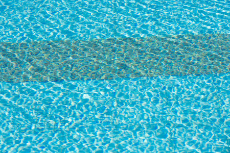 Close-up of shimmering blue water surface with intricate light reflections creating dynamic ripples, evoking a refreshing and summery ambiance.の写真素材