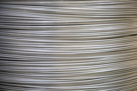Close-up of coiled aluminum wires with a smooth surface and layered overlapping pattern, soft lighting.の写真素材