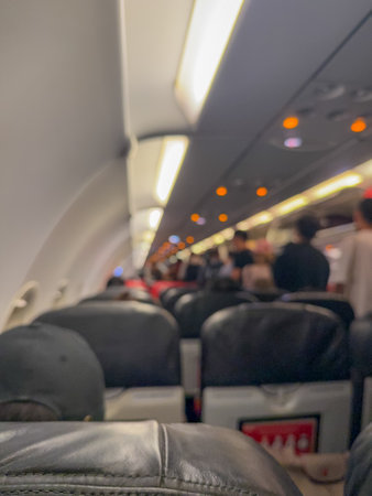 Blurred Airplane Cabin Interior showing overhead lights, seating, and passengers in a subtle, out-of-focus perspective.の写真素材