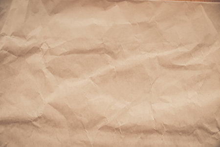 close-up of crumpled brown paper, revealing a texture reminiscent of aged parchment. The deep creases and uneven surface create a sense of time and history.の写真素材