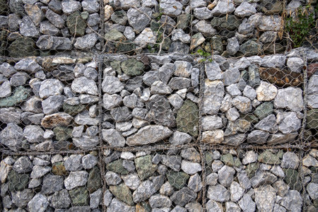 gabion wall, showcasing the texture of the grey stones and the wire mesh. The image highlights the detailed pattern and rugged nature of the construction material.の写真素材