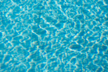 Close-up of shimmering blue water surface with intricate light reflections creating dynamic ripples,...