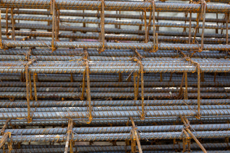 Close-up of steel rebar grid used for concrete reinforcement in construction. Showing a pattern of rusty bars, essential for building strength.の写真素材