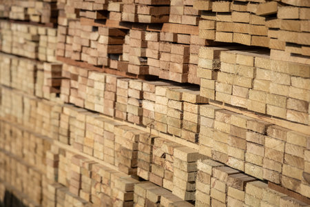 Stacked wooden planks in a lumberyard, various shades and textures, neatly arranged.の写真素材