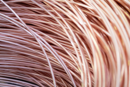 Close-up of coiled copper wires with a shiny surface, intricate overlapping pattern, warm lighting.の写真素材