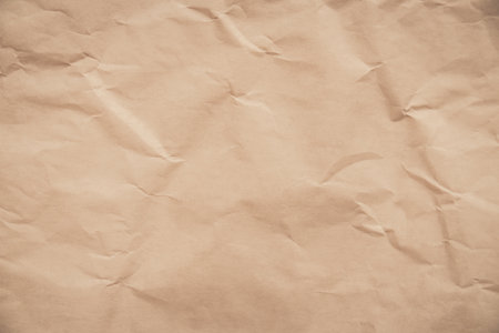 close-up of crumpled brown paper, revealing a texture reminiscent of aged parchment. The deep creases and uneven surface create a sense of time and history.の写真素材