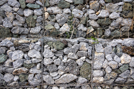 gabion wall, showcasing the texture of the grey stones and the wire mesh. The image highlights the detailed pattern and rugged nature of the construction material.の写真素材