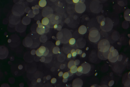 Defocused bokeh lights of different sizes and colors on a dark background.の写真素材
