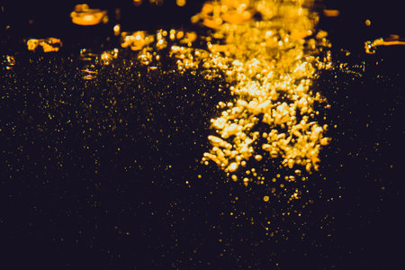 Abstract blurred golden bokeh lights against a dark background creating a warm and festive atmosphere.の写真素材