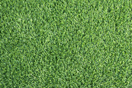 close-up of a lush, green artificial turf. The synthetic blades of grass are perfectly aligned and...