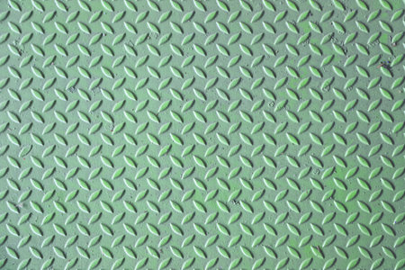 Green diamond plate metal surface with visible wear and scratchesの写真素材
