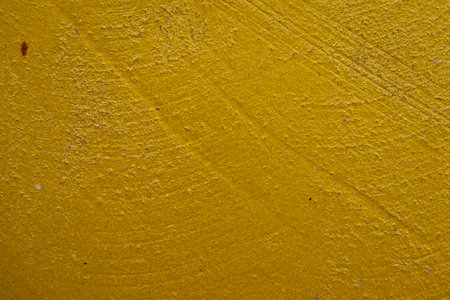 close-up shot of a textured gold yellow concrete surface. The rough and slightly uneven texture,...