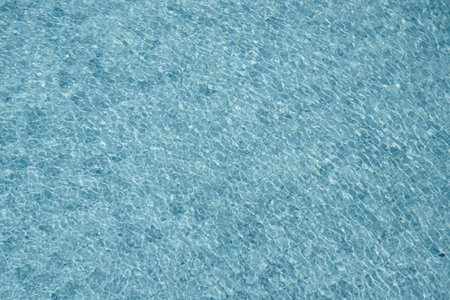 Vibrant blue water surface with shimmering reflections and ripples under sunlight.の写真素材