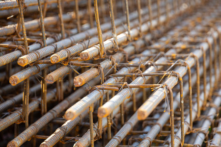 Close-up of steel rebar grid used for concrete reinforcement in construction. Showing a pattern of rusty bars, essential for building strength.の写真素材