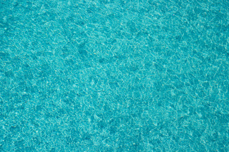 Vibrant blue water surface with shimmering reflections and ripples under sunlight.の写真素材