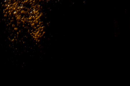 Abstract blurred golden bokeh lights against a dark background creating a dramatic and festive atmosphere.の写真素材