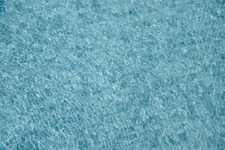 Vibrant blue water surface with shimmering reflections and ripples under sunlight.の写真素材